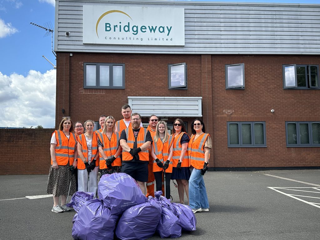 Bridgeway staff in hi-vis holding litter-picking bags outside Bridgeway House
