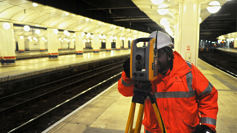 A Bridgeway surveyor using a total station on a railway station platform